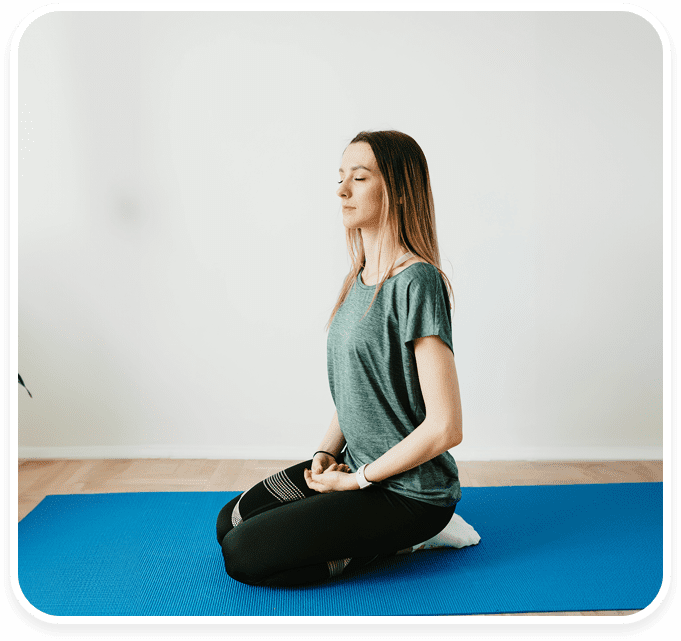 A woman sitting on the ground in a yoga pose.