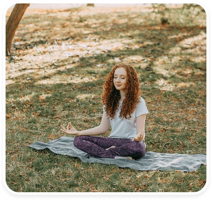 A woman sitting on the ground in a park.