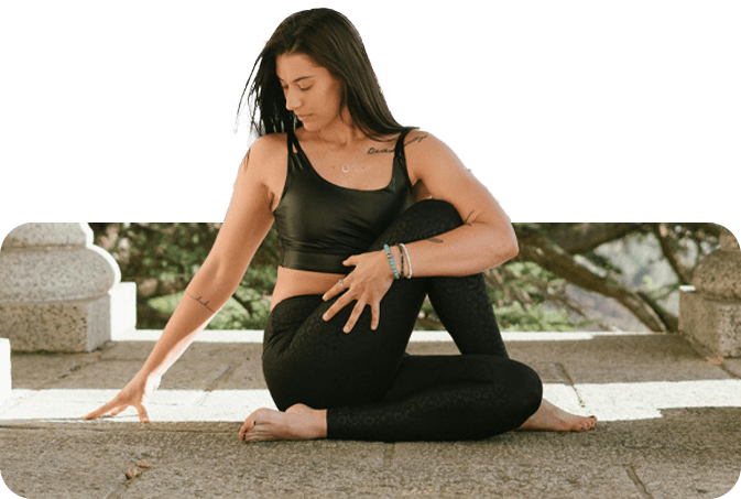 A woman sitting on the ground in a yoga pose.