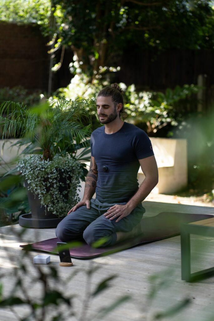 A man sitting on the ground in front of some plants.