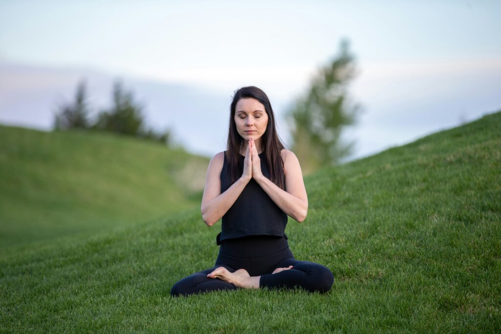 A woman sitting in the grass with her hands folded together.