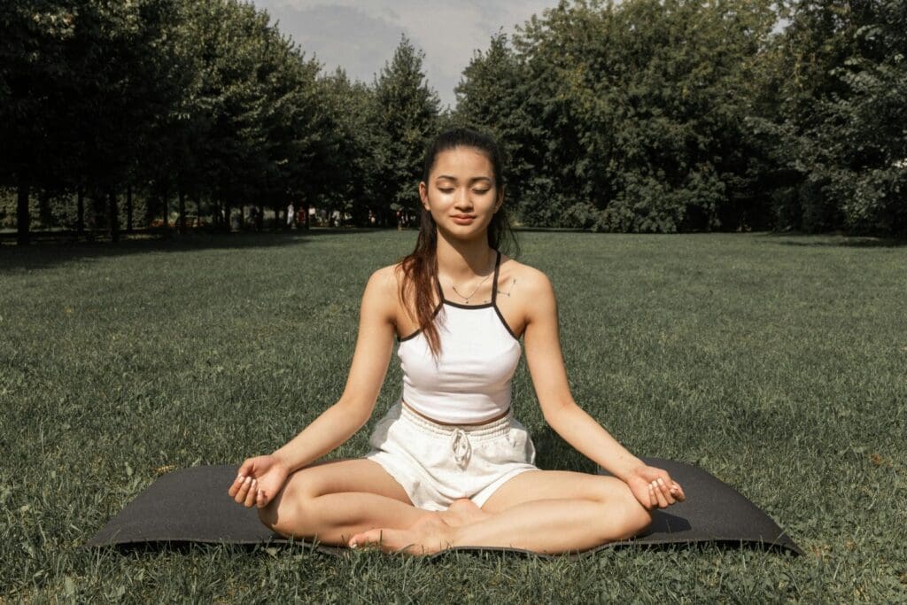 a woman in a white top is practicing meditation