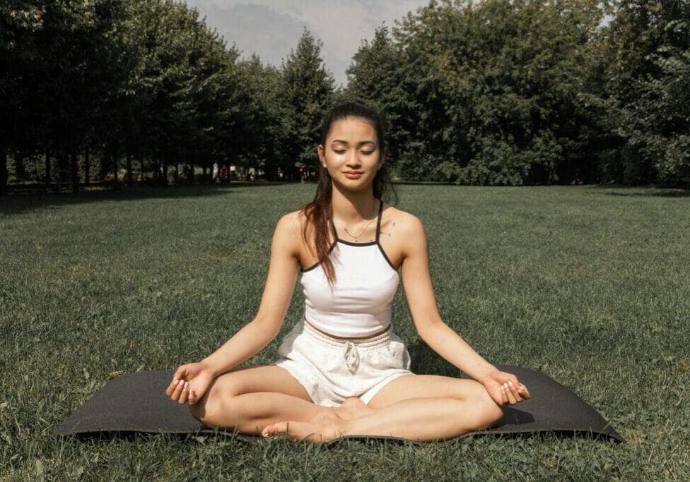 a woman in a white top is practicing meditation